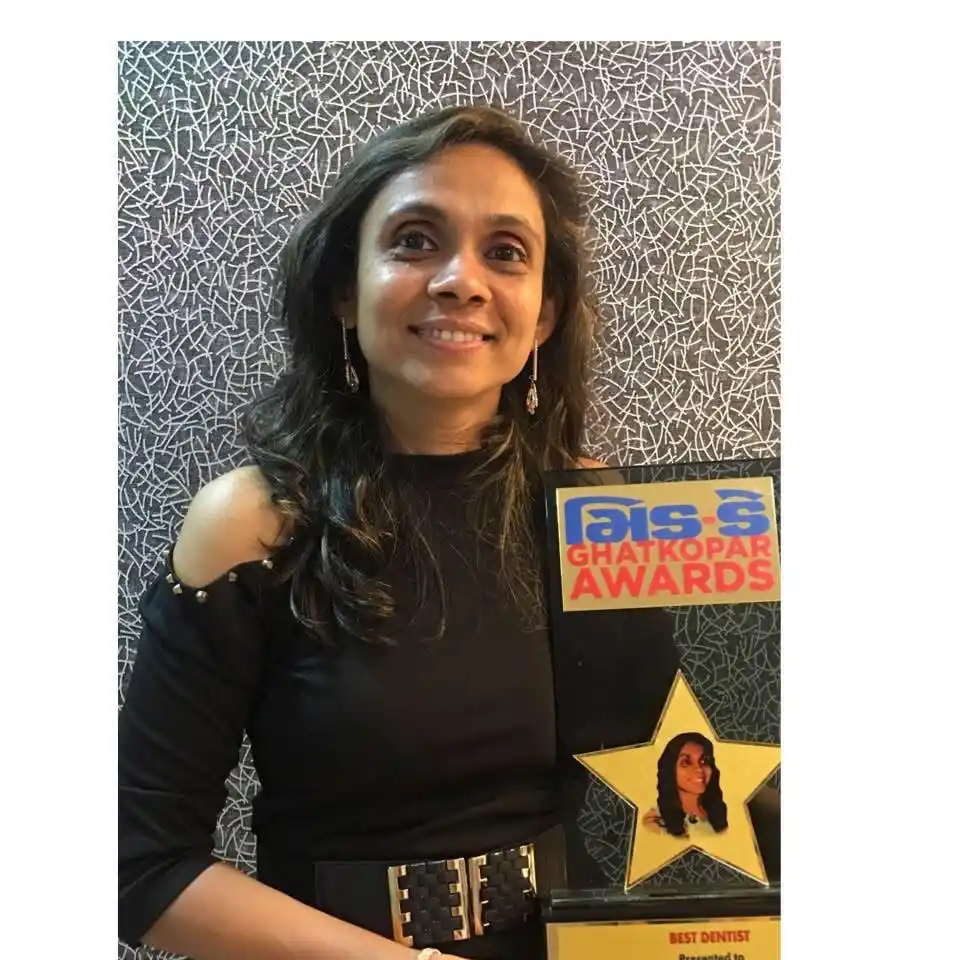 Dr. Bhavna D. Dedhia, BDS, holding her Best Dentist award at her Ghatkopar East dental clinic